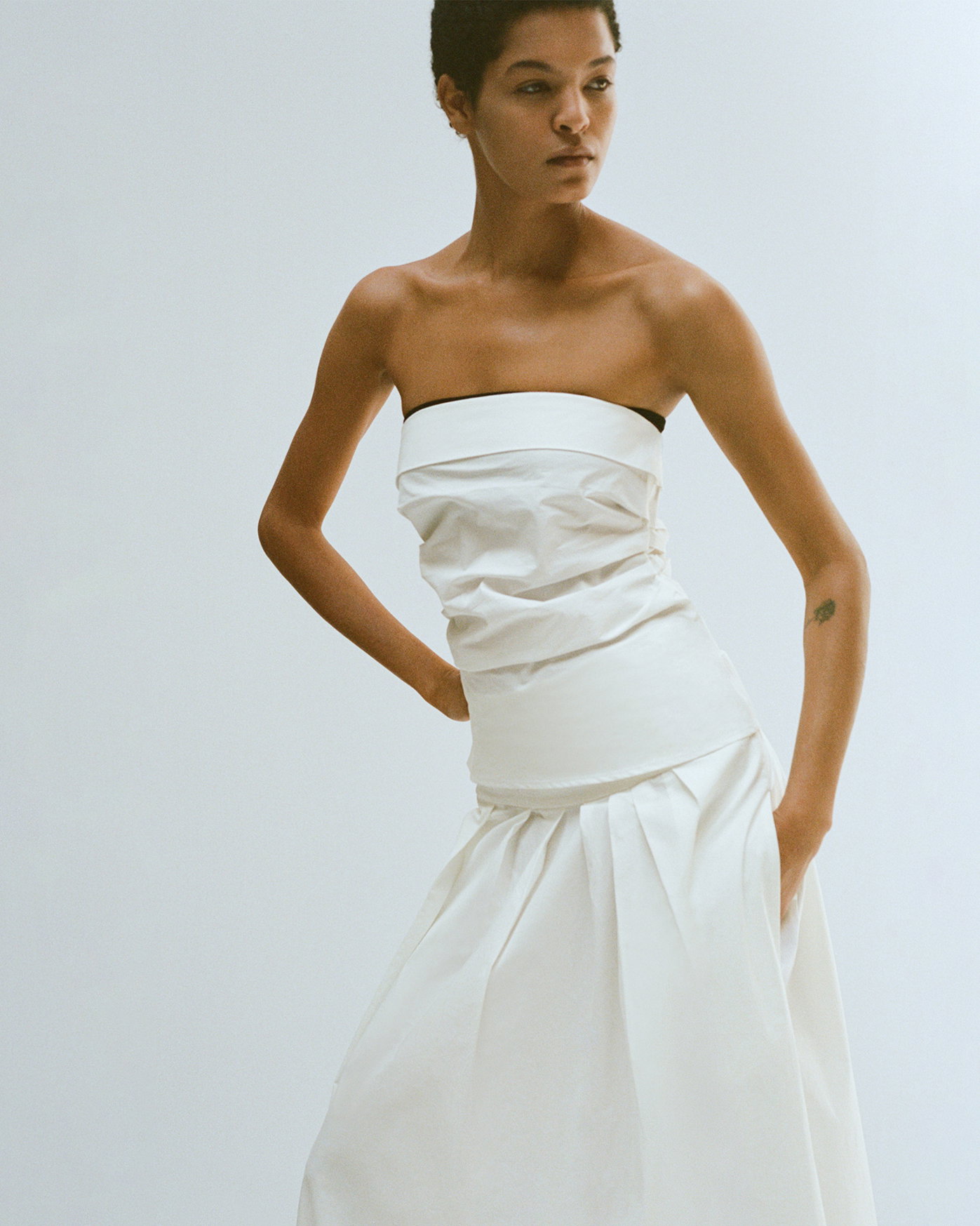 Model standing against white background wearing Maisy Strapless Top in Poplin in White and Nessa Skirt in Poplin in White