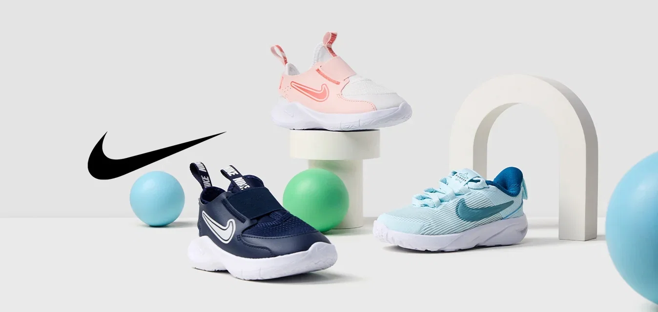 Drei Paare Nike-Schuhe: ein rosa-weißes Slip-On, ein navyfarbenes Slip-On und ein hellblaues mit Schnürsenkeln. Umgeben von bunten, runden Requisiten.