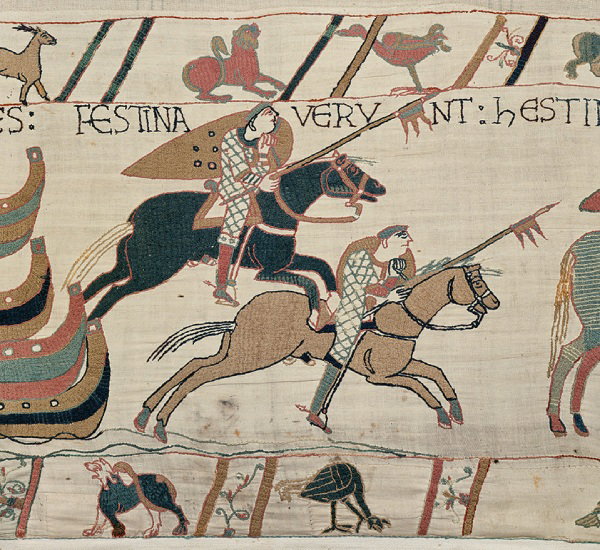 Scene from the Bayeux Tapestry showing two galloping horsemen carrying shields and spears.