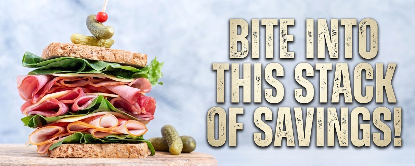 A tall sandwich with ham, cheese, and lettuce, next to text that says "BITE INTO THIS STACK OF SAVINGS!".