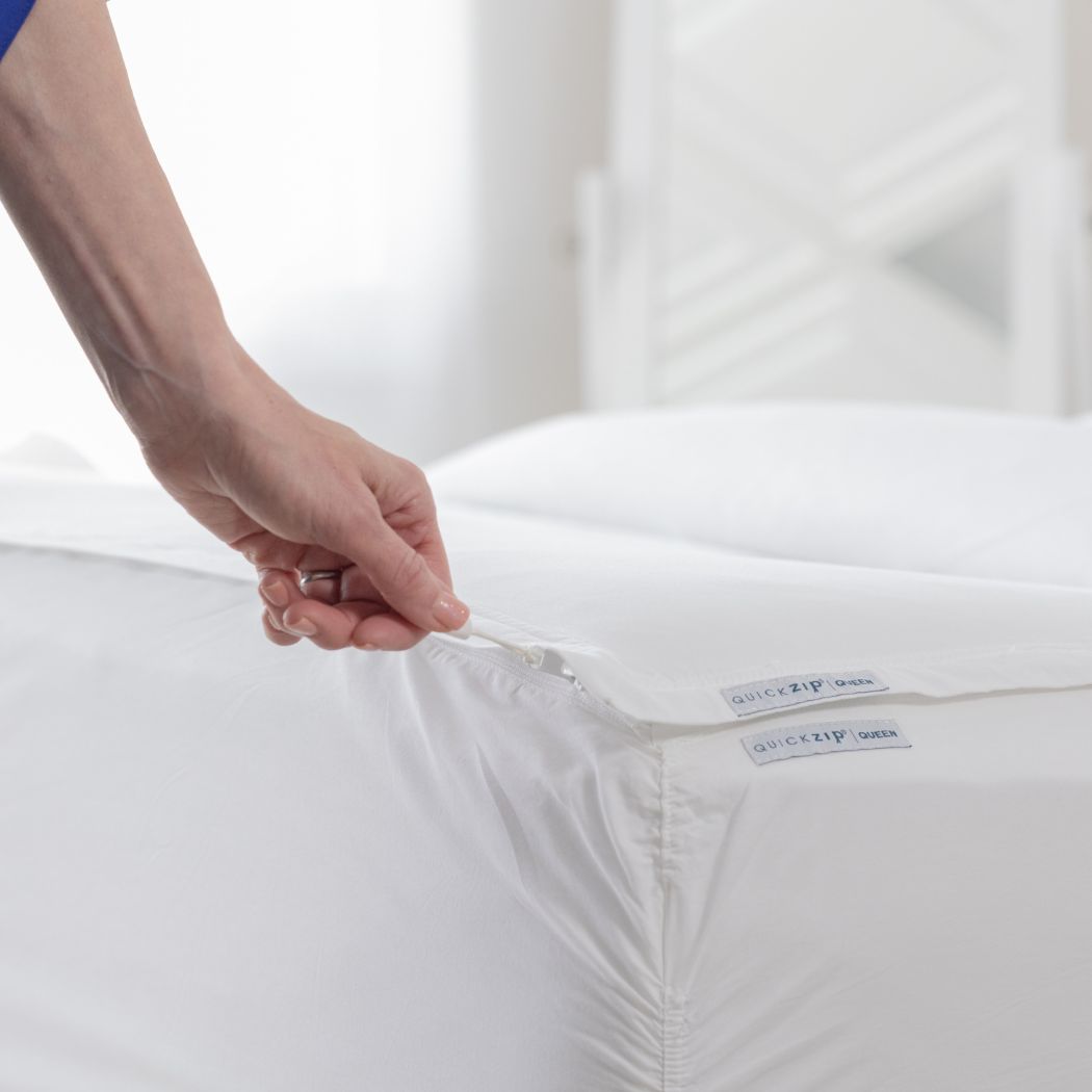 image shows a hand unzipping the fitted sheet from the mattress