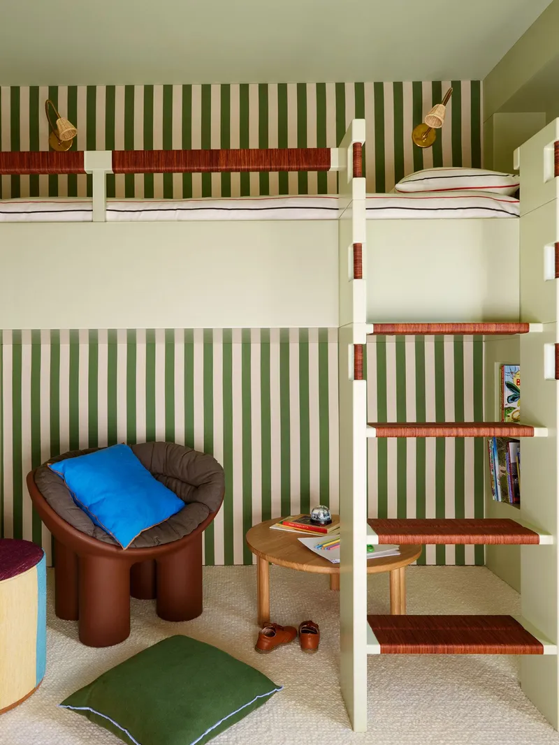 Kids' room wallpaper in white and green stripes behind a loft bed.