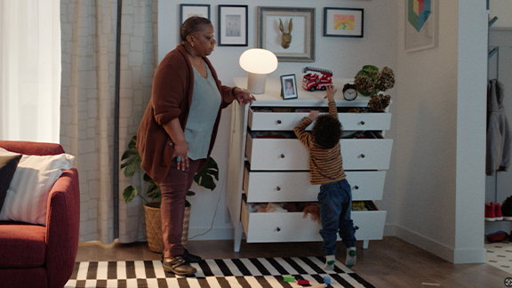 Woman prevents dresser from tipping over onto child.