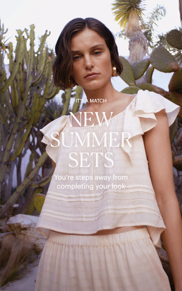 It's A Match: New Summer Sets - You're steps away from completing your look. Woman wearing a light peach cotton blouse and maxi skirt set with white sandals, posed outdoors surrounded by greenery.