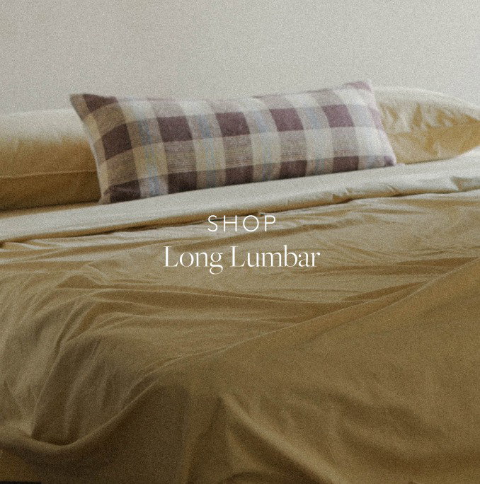 Detail of a brown check lumbar pillow on yellow bedding