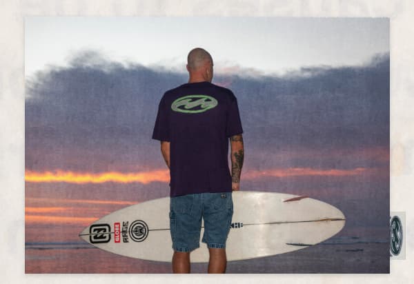 Bad Dog Collection on a surfer with a board looking at the ocean