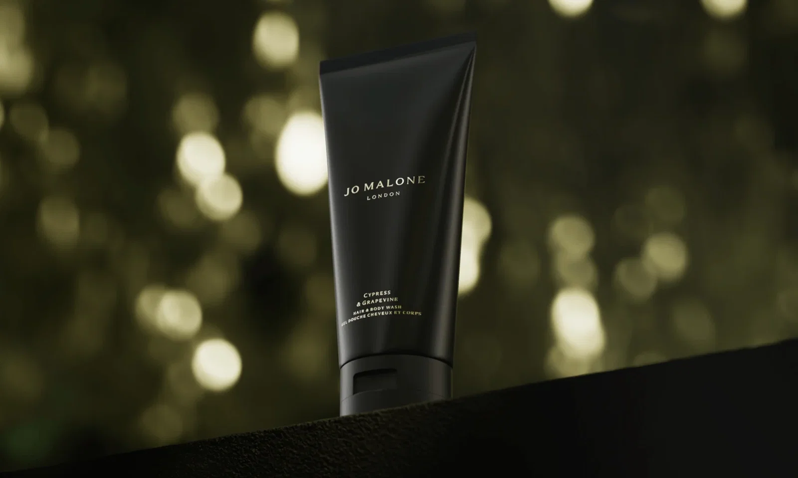 Cypress & Grapevine Hair & Body Wash against a softly blurred, warm bokeh background.