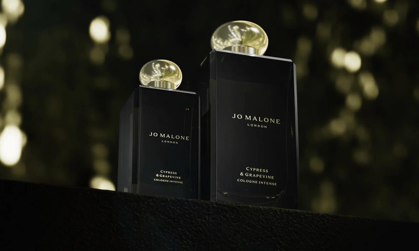 Two bottles of Cypress & Grapevine Cologne Intense against a softly blurred, warm bokeh background.