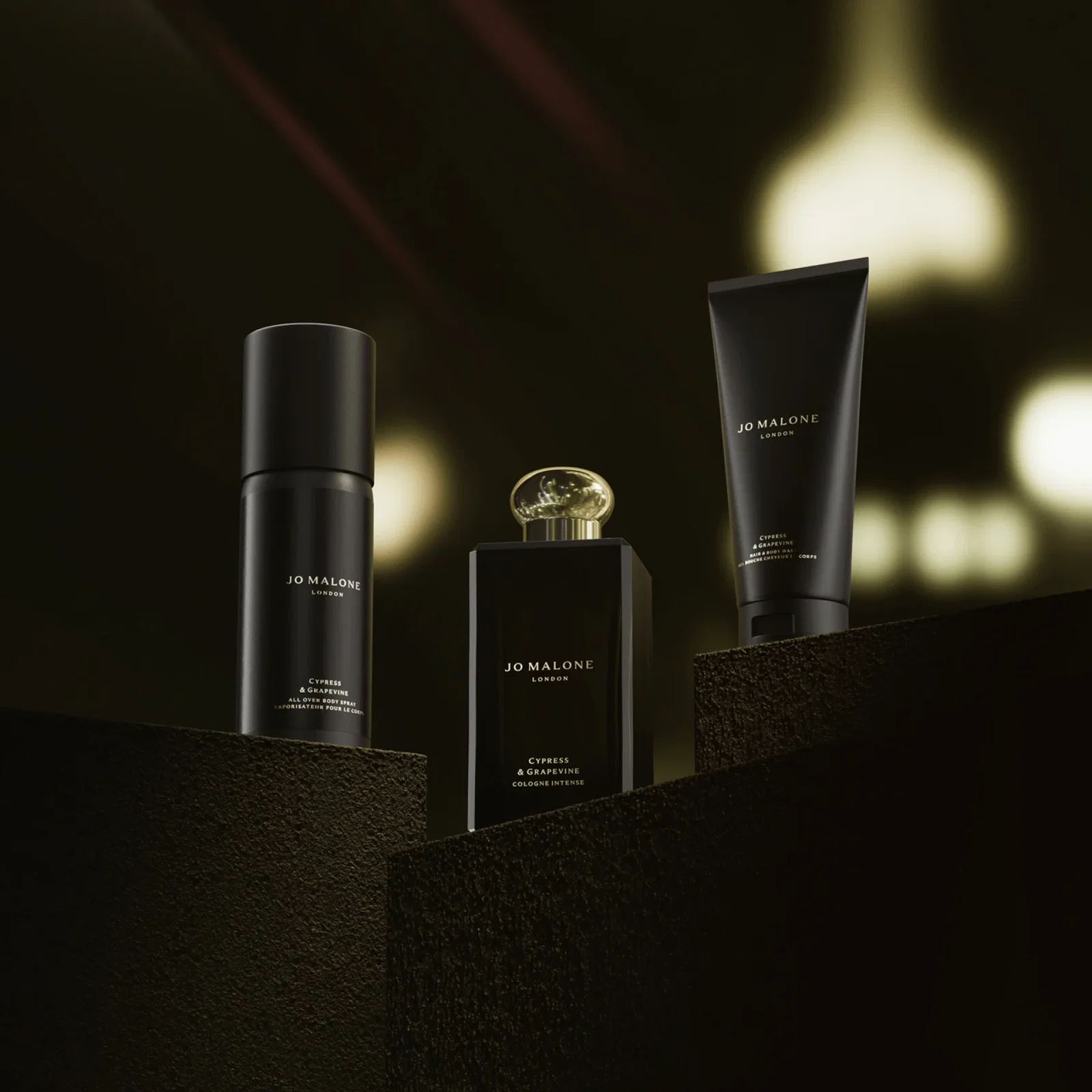 Cypress & Grapevine grooming essentials arranged on textured, dark brown platforms, against a softly blurred, warm bokeh background.