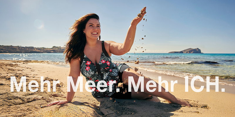 Ein Model am Strand, sie trägt einen Tankini mit tropischem Print. Darunter der Text: Mehr Meer. Mehr ICH.