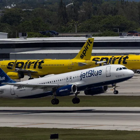 A JetBlue Airlines plane takes off near Spirit Airlines planes at the Fort Lauderdale-Hollywood International Airport on May 16, 2022, in Fort Lauderdale, Florida.