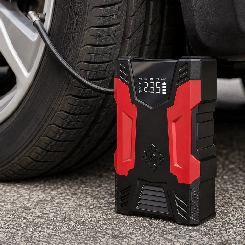 Digital tire pressure gauge with red and black design displayed on pavement next to vehicle tire and air hose.