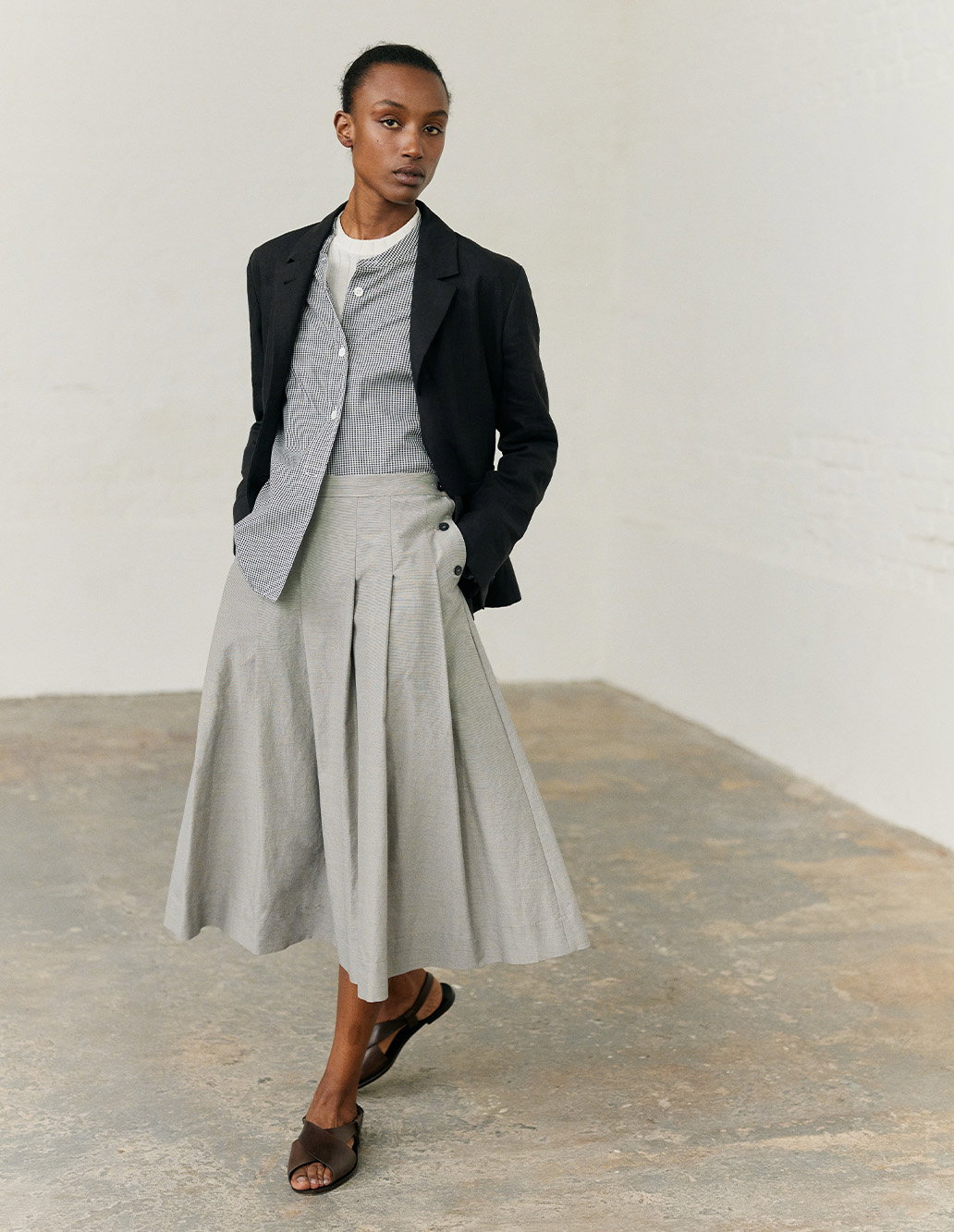 Black tailored jacket worn with shirt and pleated light skirt