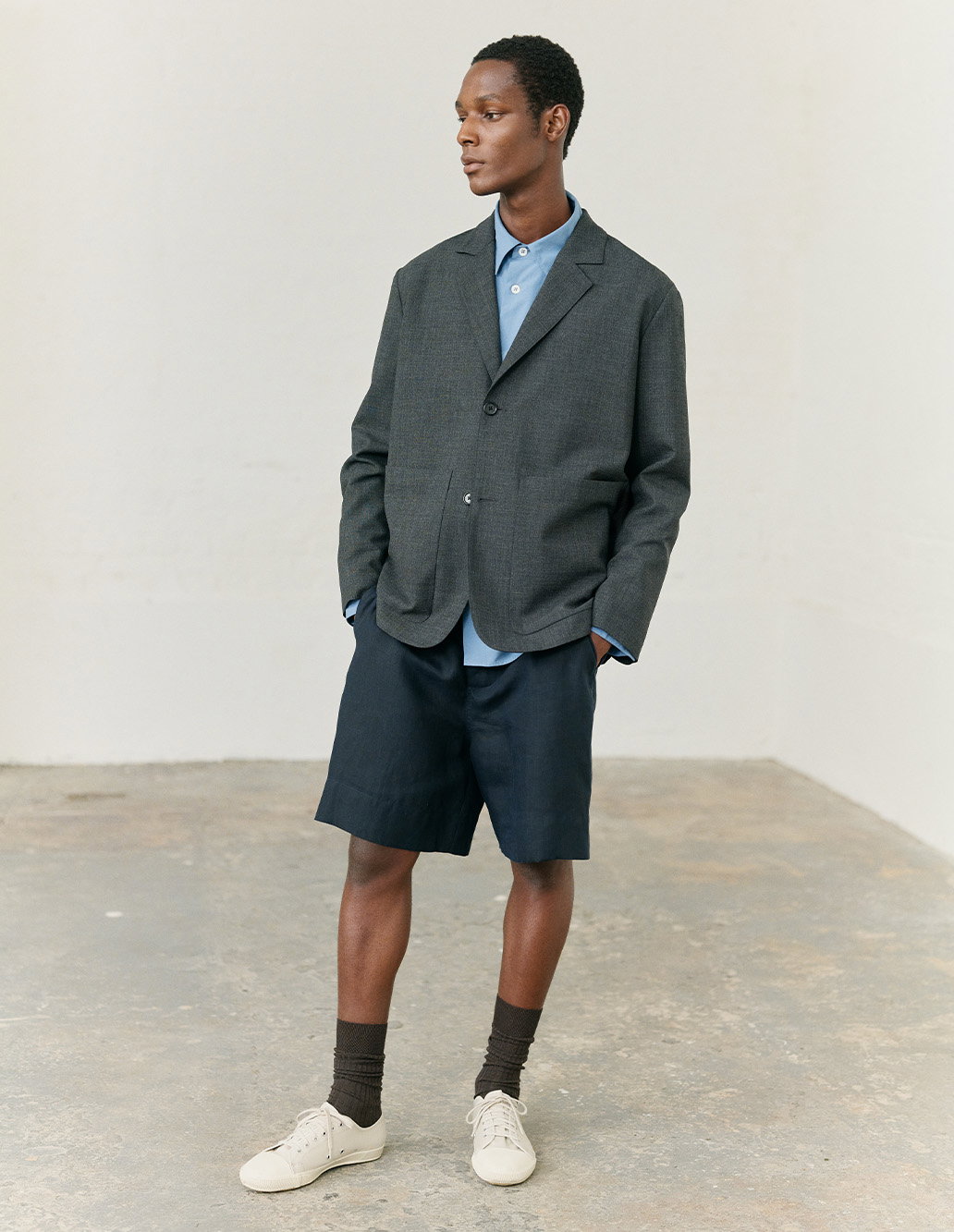 Relaxed grey blazer paired with shorts and trainers
