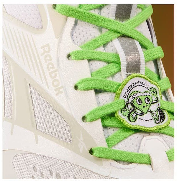 Close-up of a white Reebok FloatZig 2 running shoe with bright green laces and a Solemates patch attached to the laces.