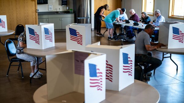 Voters fill out ballots at Lowe Park Arts and Environment Center. They sit at booths with pictures of American flags.