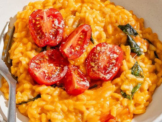 Tomato risotto topped with tomatoes in a bowl with a fork.