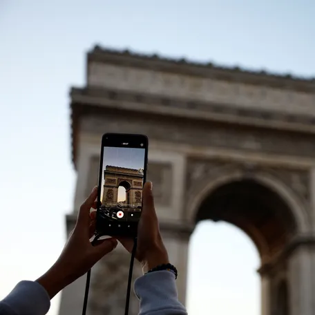 Tourists take pictures in front of the Arc de Triomphe as the sun sets over Paris on Oct. 24, 2024.