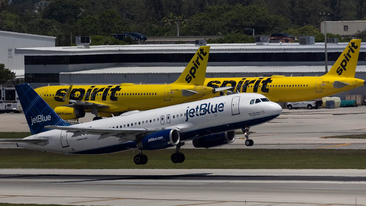 A JetBlue Airlines plane takes off near Spirit Airlines planes at the Fort Lauderdale-Hollywood International Airport on May 16, 2022, in Fort Lauderdale, Florida.