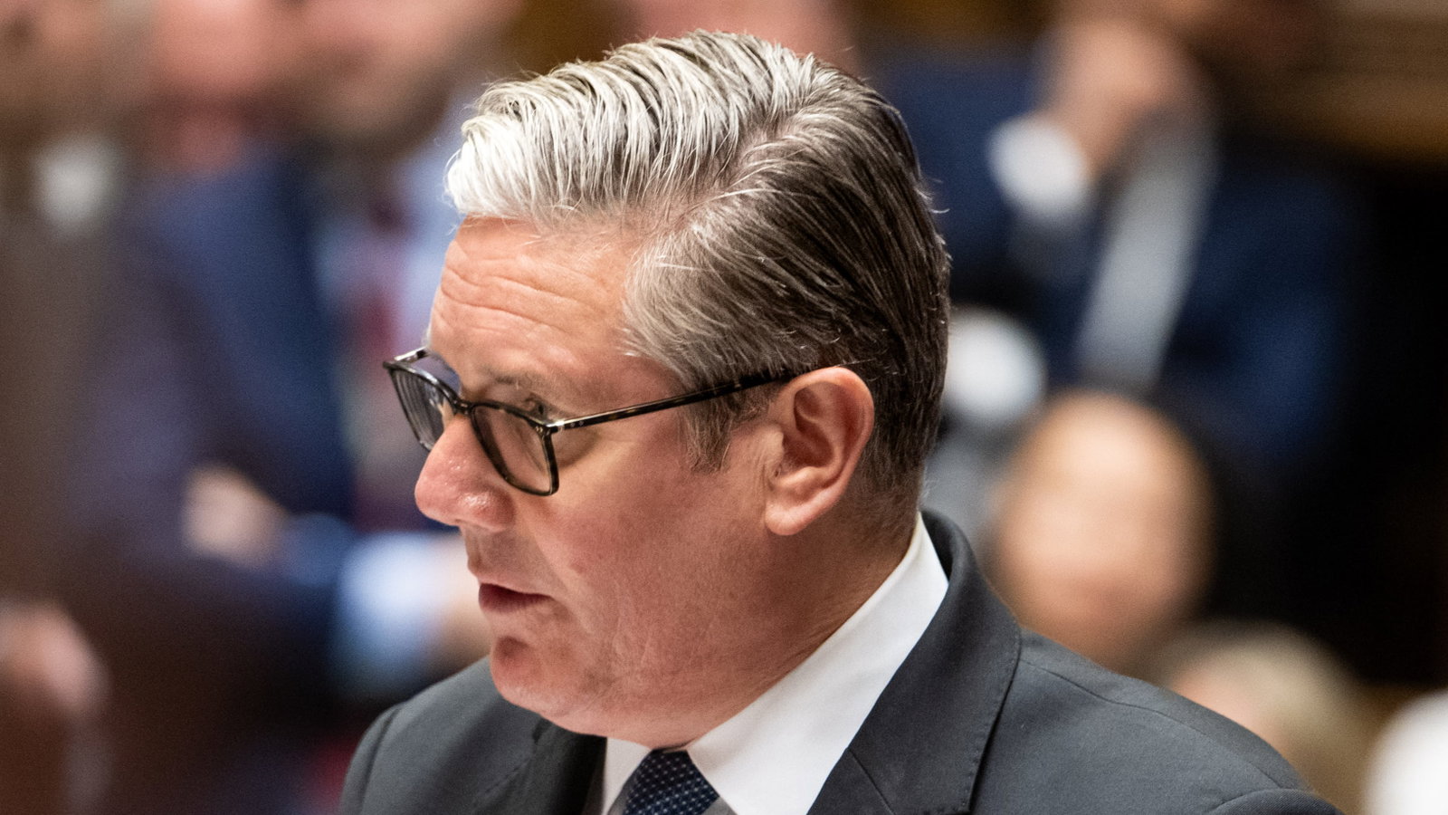Close-up of Keir Starmer speaking at PMQs, wearing glasses and a suit, white shirt and tie.