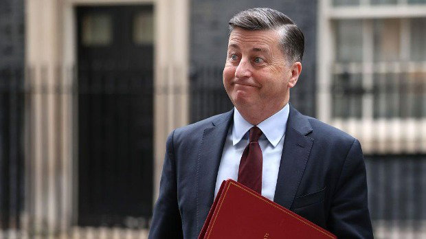 Peter Alexander leaves Downing Street wearing a dark suit and holding a red folder.