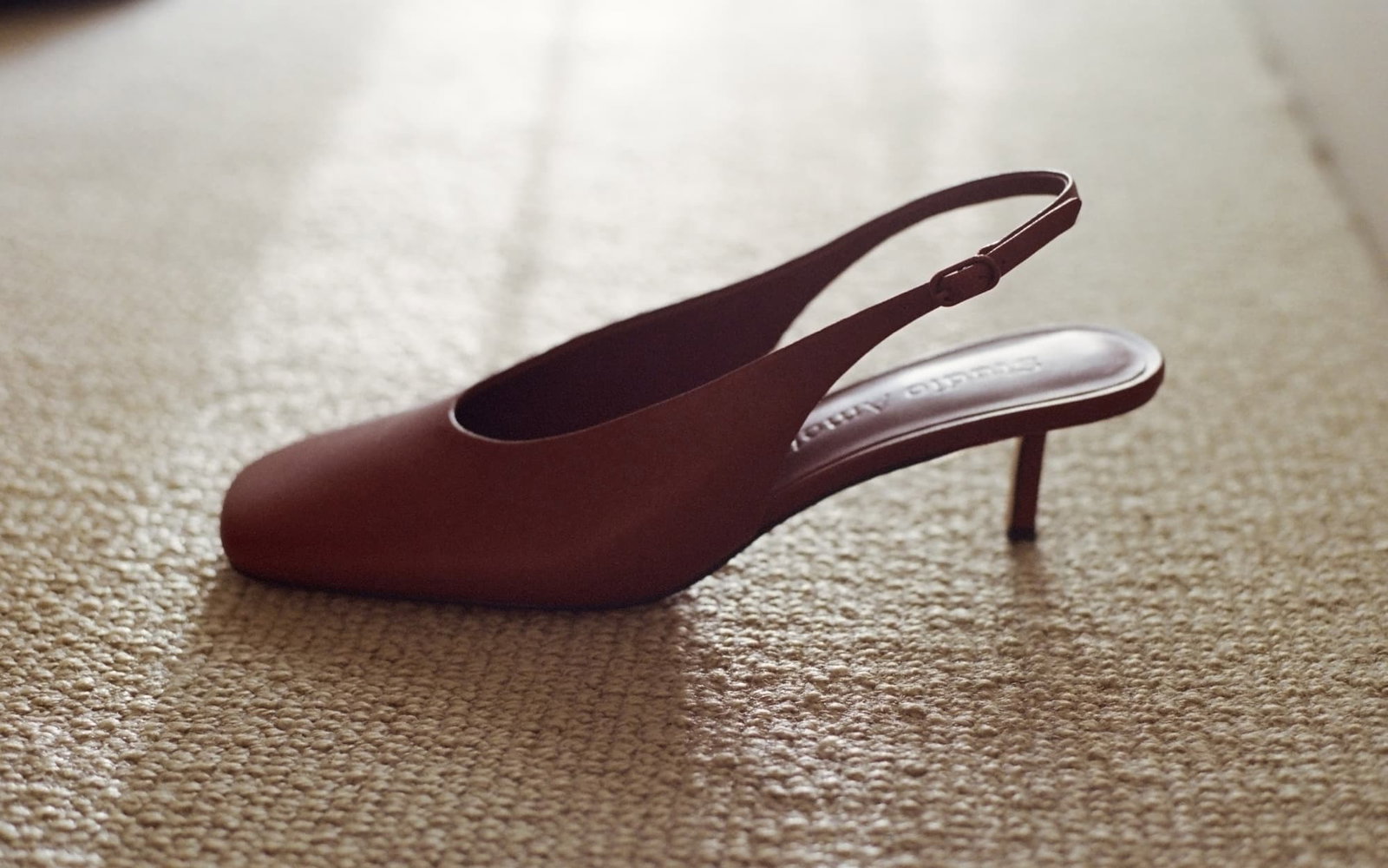 A close up of a red leather pump with a kitten heel