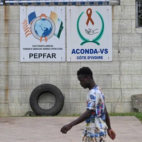 A pedestrian walks past a PEPFAR (the U.S. President’s Emergency Plan for AIDS Relief) sign in Abidjan, Ivory Coast, on July 12, 2025.