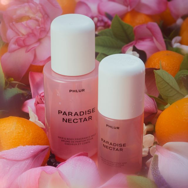 Two pink bottles labeled 'PARADISE NECTAR' amidst pink flowers and oranges.