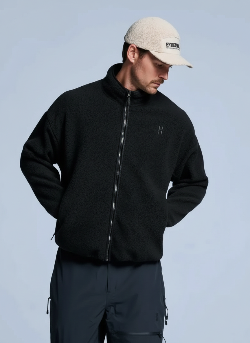 Man wearing a black fleece jacket and beige cap.