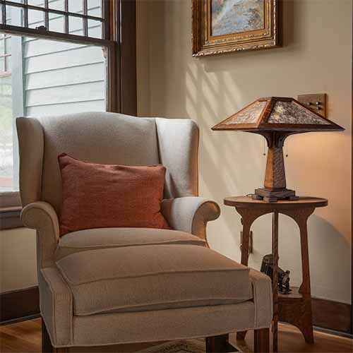 A wood and mica table lamp sits next to an upholstered chair.