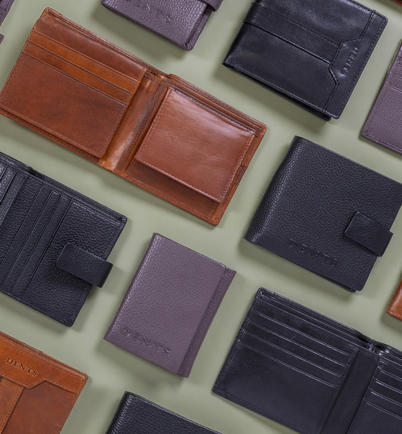 Various men's wallets on a green background from different collections and in brown and blacks. 