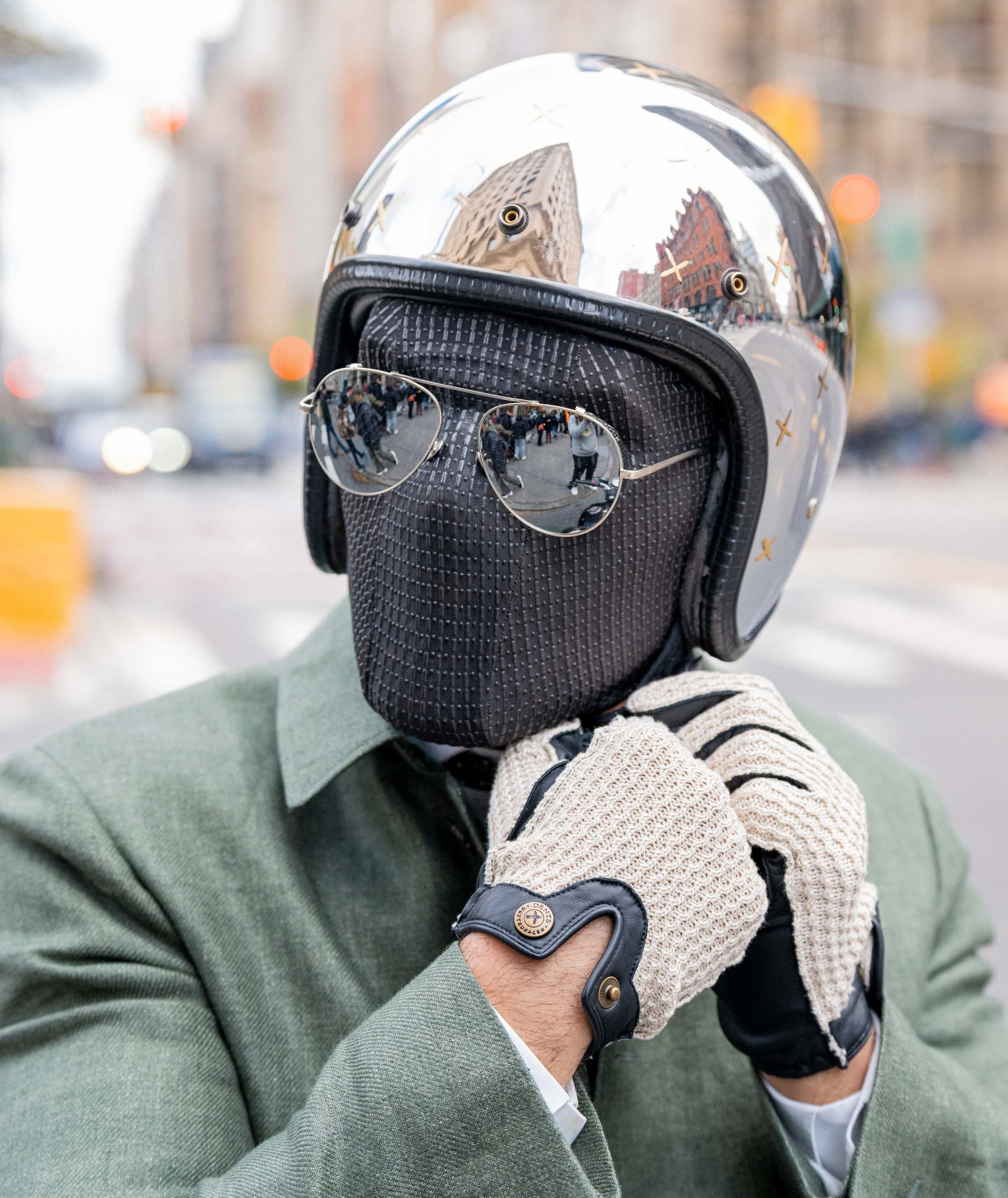 Man wearing suited racer touchscreen crochet back leather driving gloves in black while putting on helmet. 