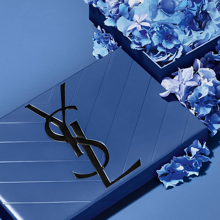 A blue quilted YSL gift box accompanied by elegant blue flowers.