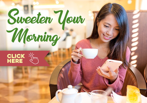 Woman laughing while holding a drink and looking at a burger and fries.
