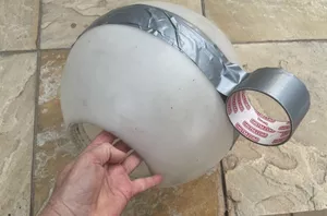 She wraps tape around a plastic lampshade to beautify her backyard