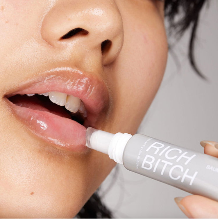 Model applying rich bitch lip balm