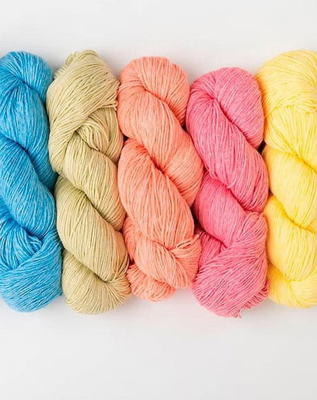  Five skeins of yarn in blue, tan, bright coral, bright pink, and sunny yellow. >>