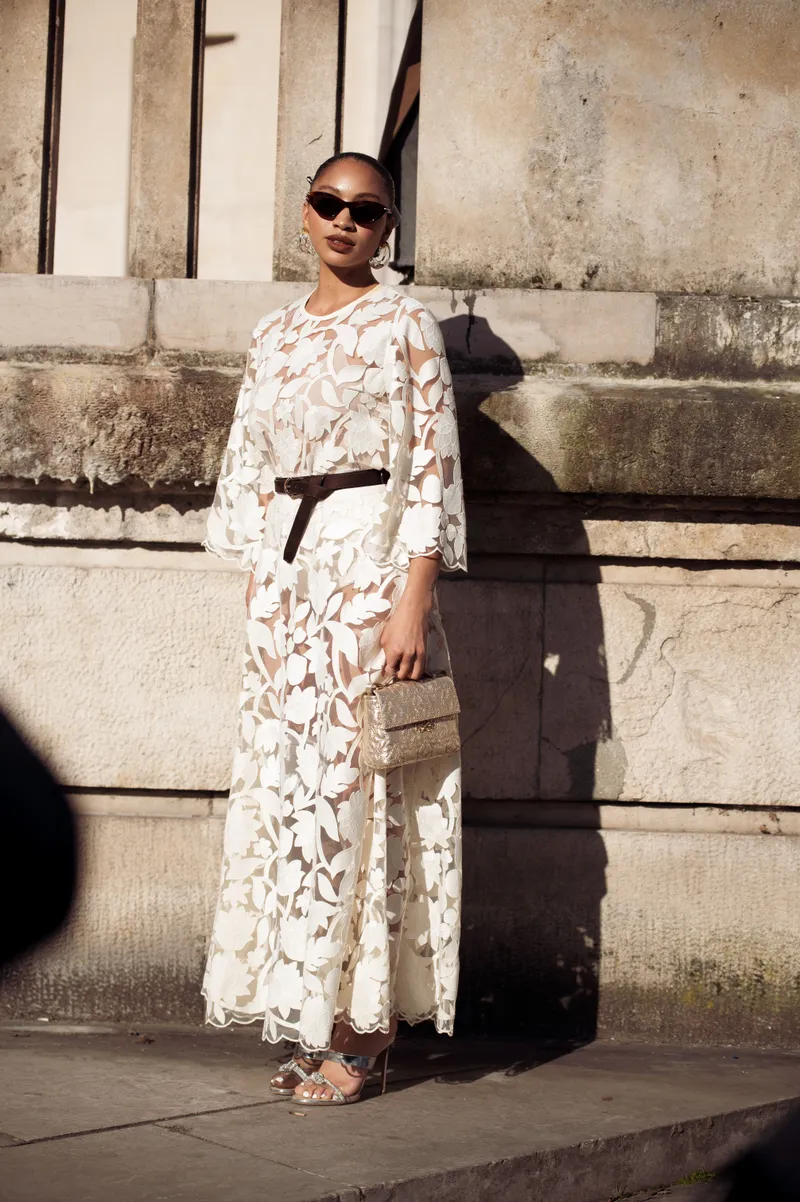 how to style a long-sleeve dress for summer - PARIS, FRANCE - MARCH 08: A guest wears long white lace dress with black belt and white bag outside the Elie Saab fashion show during the Womenswear Fall/Winter 2025/2026 as part of Paris Fashion Week on March 08, 2025 in Paris, France. (Photo by Raimonda Kulikauskiene/Getty Images)