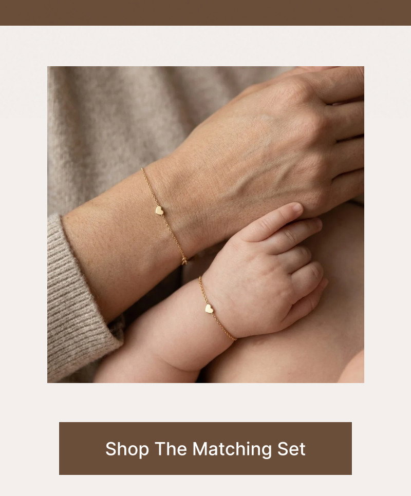 Adult and child wearing matching heart bracelets while holding hands, shown above a brown button reading Shop The Matching Set.