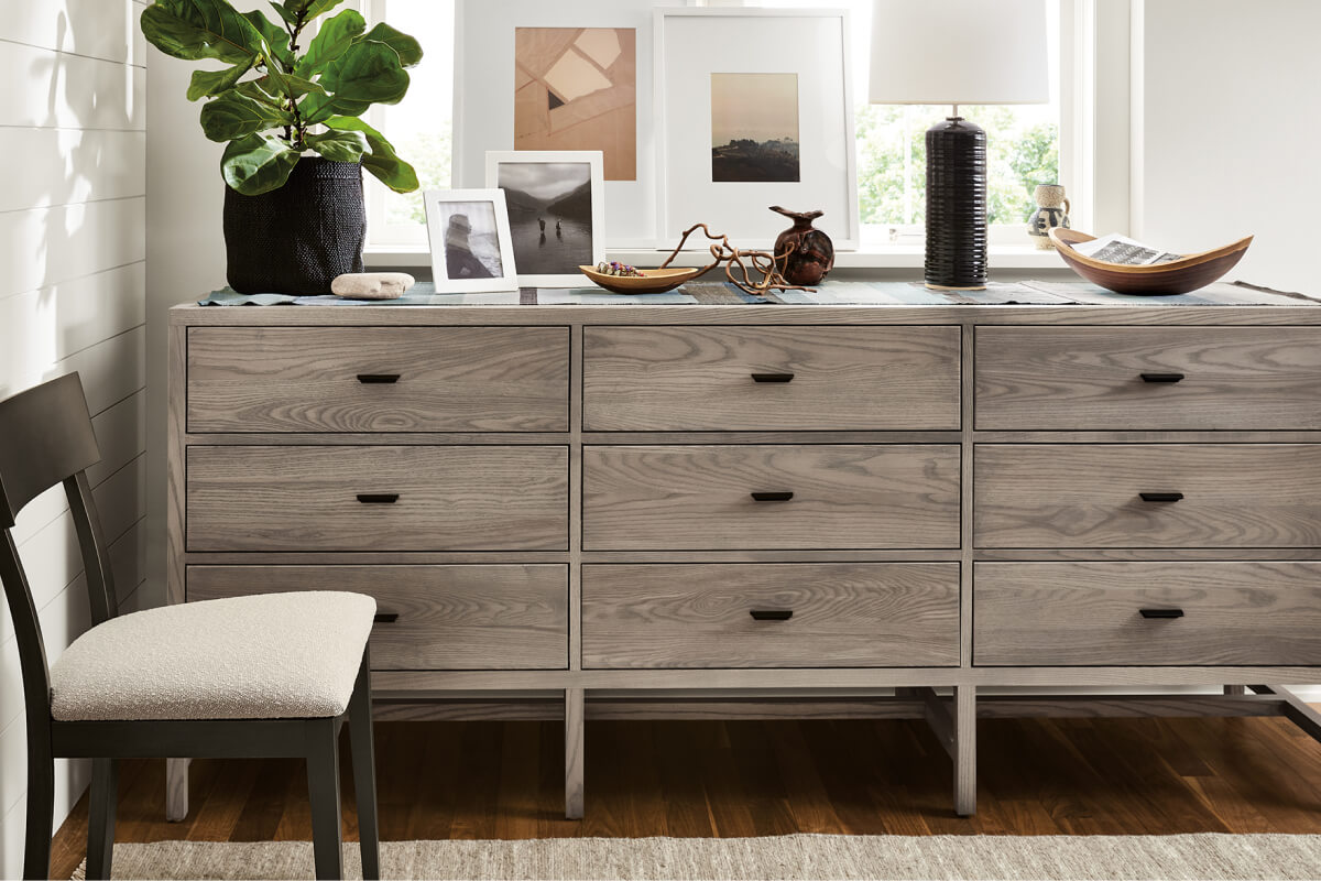 Berkeley dresser with nine drawers, grey wood finish and black hardware styled with framed artwork and decor.