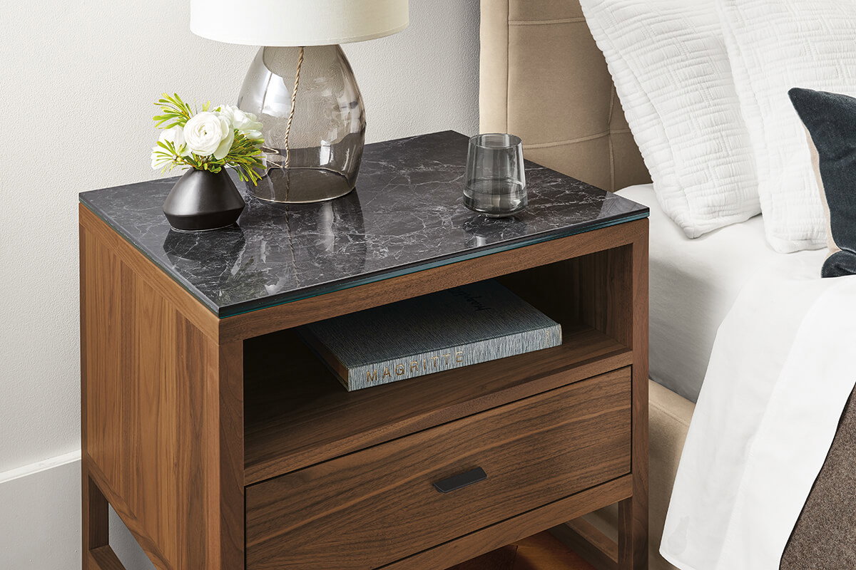Walnut Berkeley nightstand with black stone top styled with a lamp, vase and decorative accents.