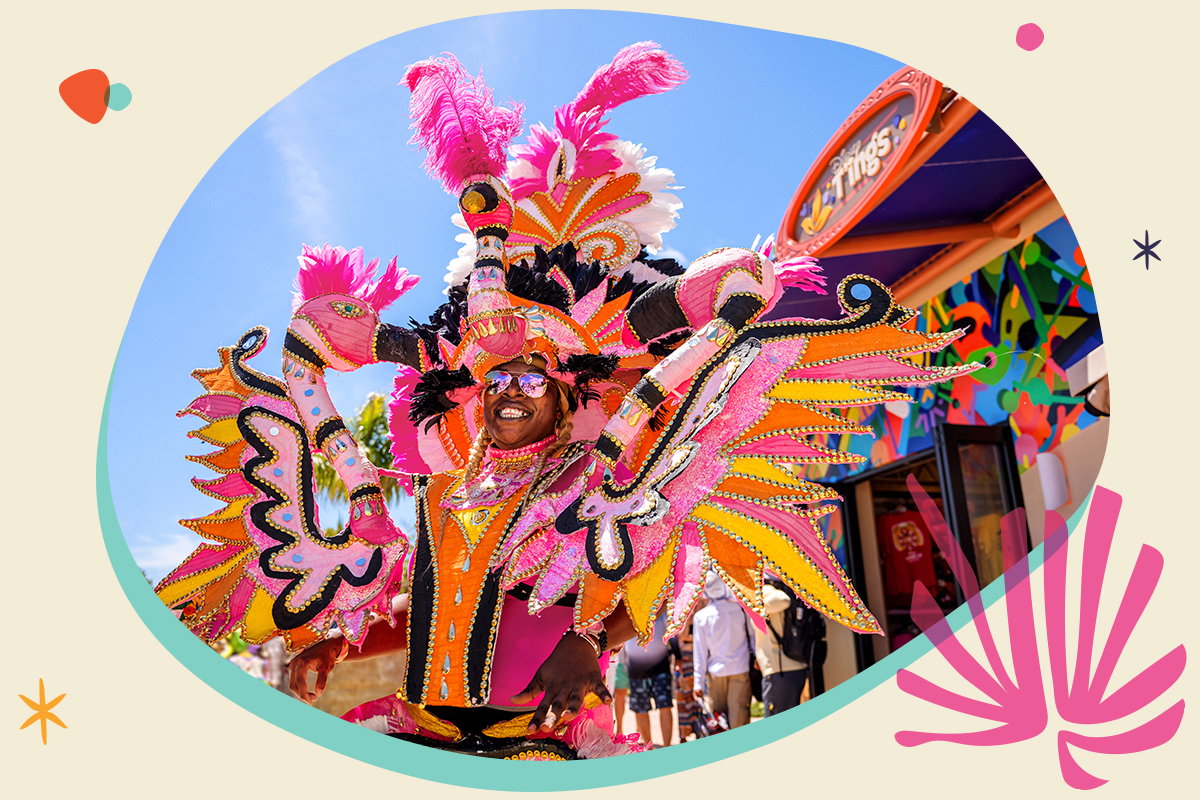 A Junkanoo performer smiles in a bright pink and orange flamingo-inspired costume.