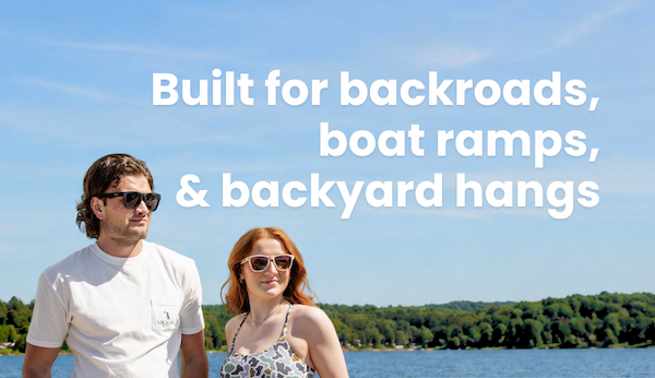 Built for backroads, boat ramps, and backyard hangs. Image of male and female models standing on the shore of a lake.