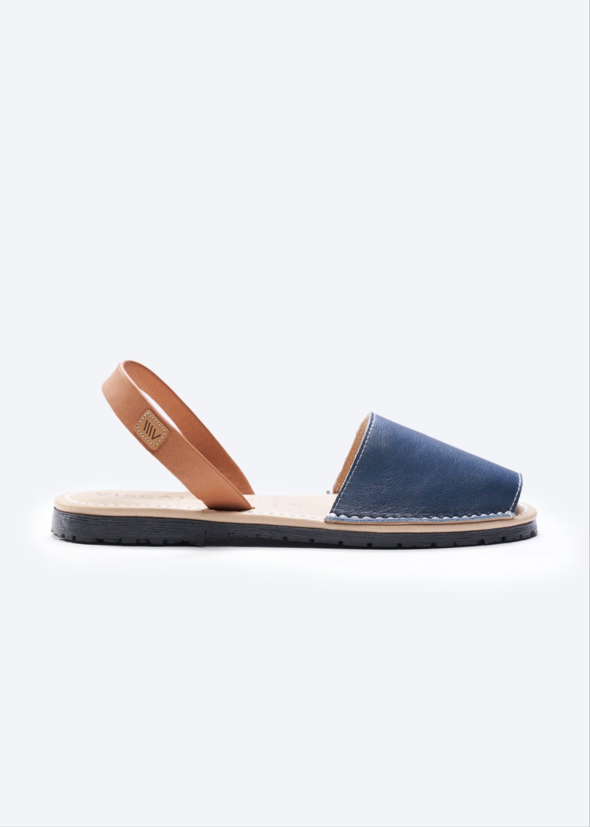 Navy leather slingback sandal with tan ankle strap, open toe, and flat espadrille sole for sunlit strolls