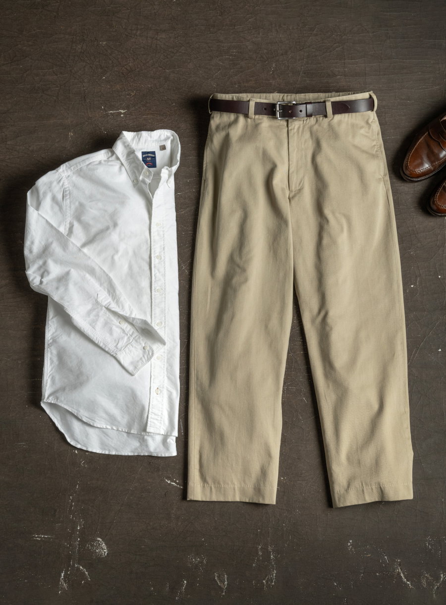 A white Bills Khakis standard fit shirt and signature style Bills Khakis Khaki lay on an industiral surface
