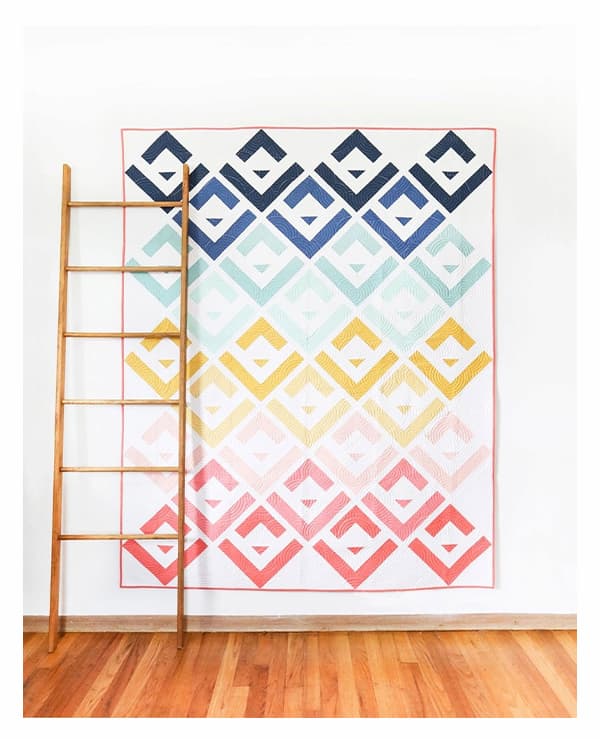 A quilt featuring log cabin blocks and shades of pinks, yellows, aquas, and blues. >>