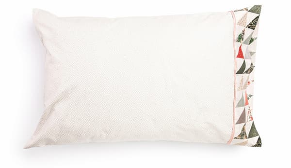 A white pillowcase with half-square triangle blocks at the opening >>
