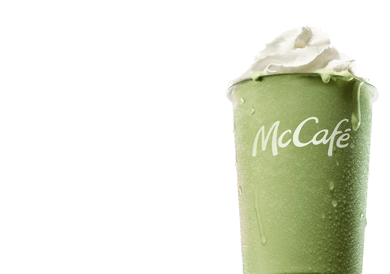 An icy, refreshing matcha latte on a blue-pink gradient background. As you scroll down the page, large white text is revealed reading 'Make it a matcha summer. Matcha blended with ice, topped with whipped cream, sweetened with vanilla'.