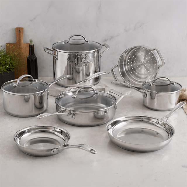 A set of stainless steel cookware, including pots, pans, and a colander, arranged on a kitchen countertop.