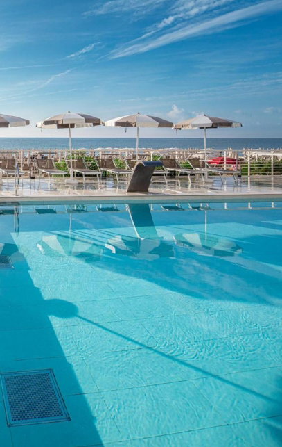 Hotel pool mit liegen und sonnenschirmen und Meerblick
